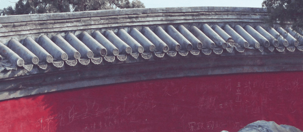 朱红宫墙与灰色筒瓦的特写，墙面上布满了历代游客刻下的字迹