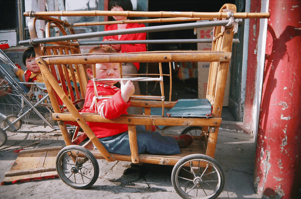 阳光下的竹制童车与红衣孩童