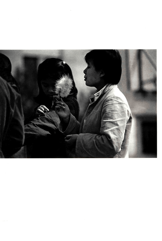 一张黑白老照片，一位短发女子侧身站立，身旁是一个手持蒲公英（或白色绒球）的小女孩，背景虚化